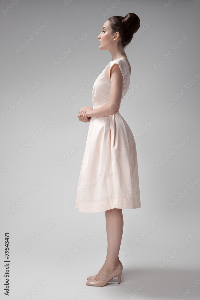 Beautiful woman in pink retro dress. Gray background. Beautiful woman in pink retro dress. Gray background.
