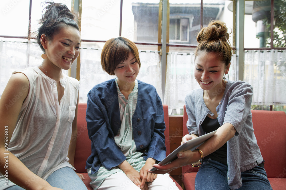 Three women looking at a digital tablet, sitting indoors. Three women looking at a digital tablet, sitting indoors.
