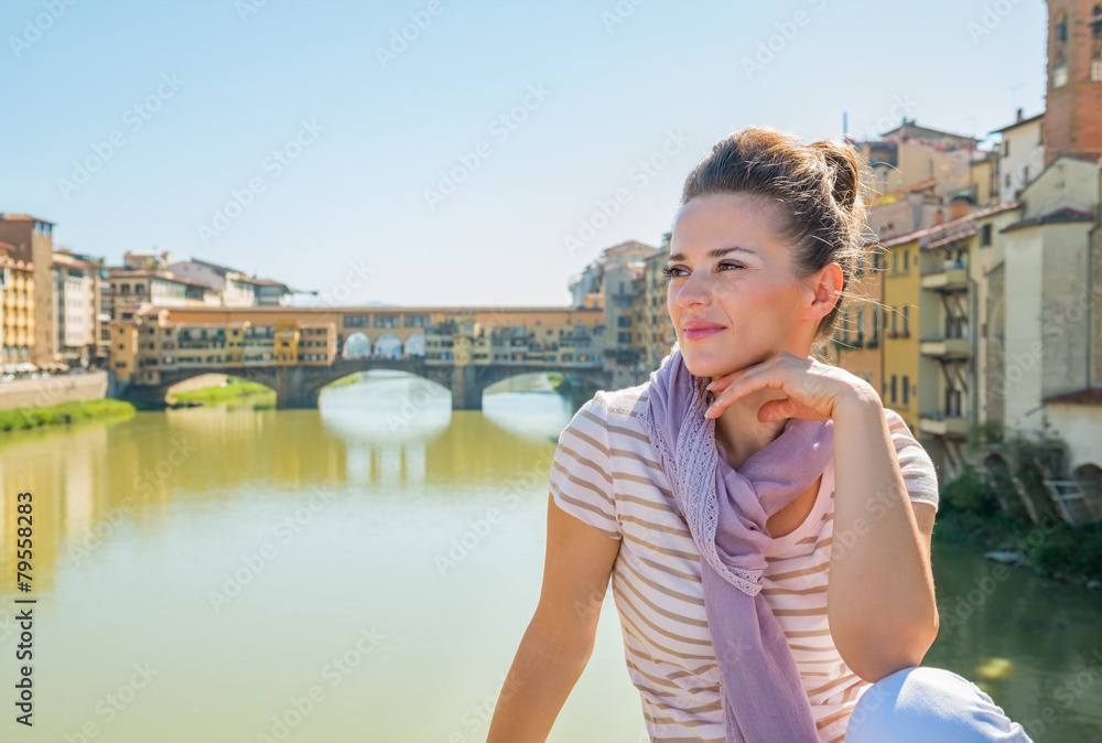 Woman sitting on bridge overlooking ponte vecchio  in florence