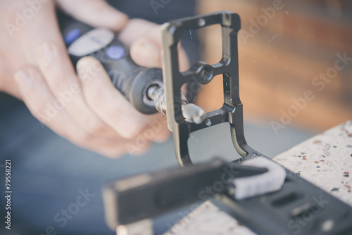 Sanding a miniature figure in the clutch with a dremel machine photo