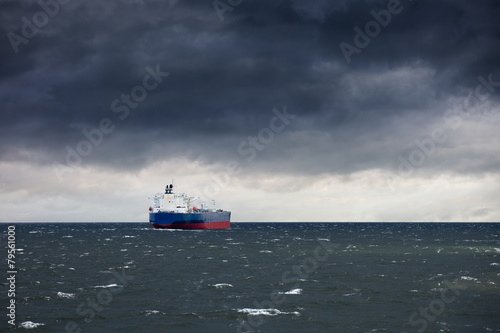 Dark cloudy stormy sky with ship and waves in the sea.