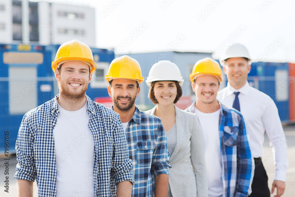 group of smiling builders in hardhats outdoors group of smiling builders in hardhats outdoors