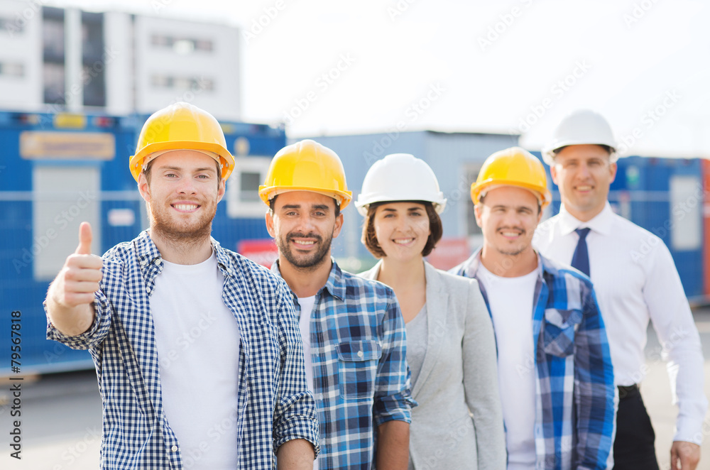 group of smiling builders in hardhats outdoors group of smiling builders in hardhats outdoors