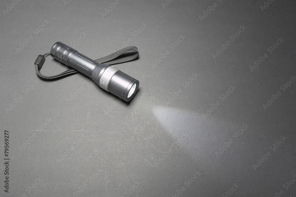 Naklejka premium Glowing metal flashlight with wrist strap