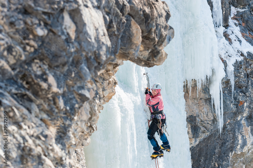 Woman mountaineer climbs on vertical icefall