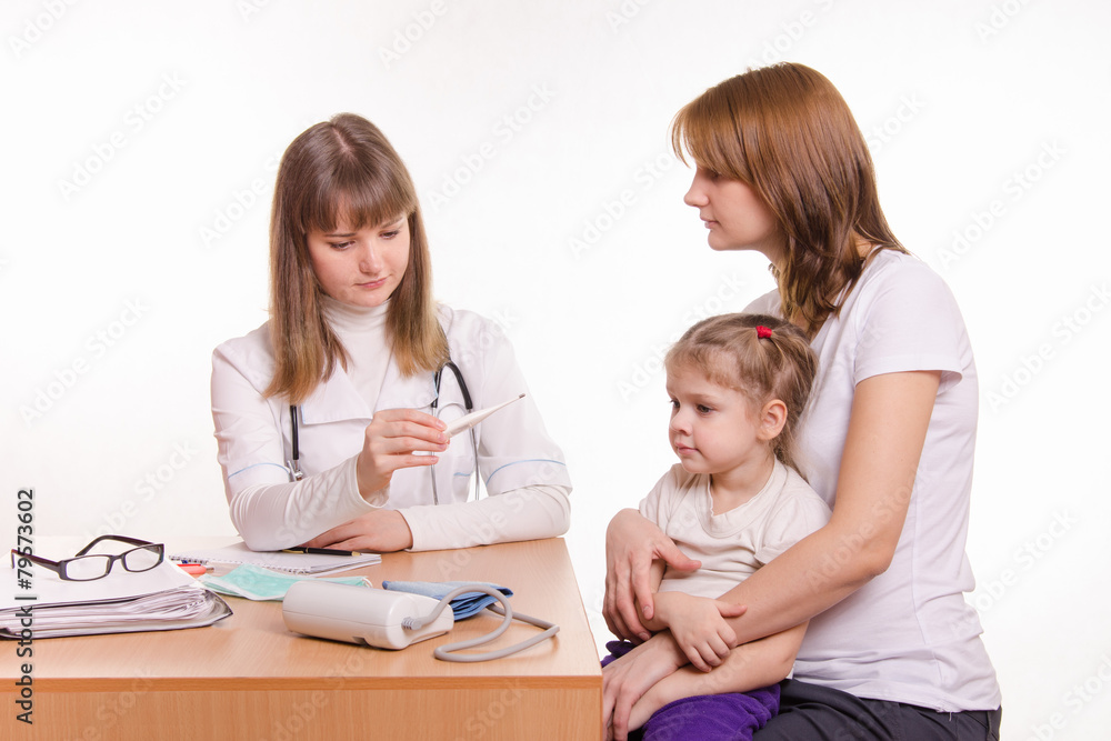 A pediatrician looks at thermometer, sitting next to a woman A pediatrician looks at thermometer, sitting next to a woman