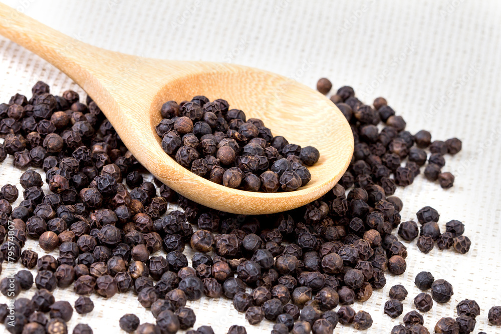 closeup black pepper in wooden spoon on fabric closeup black pepper in wooden spoon on fabric