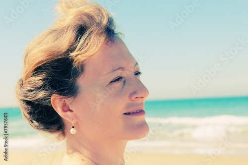 Beautiful girl smiling on the beach with the sand, sea and blue