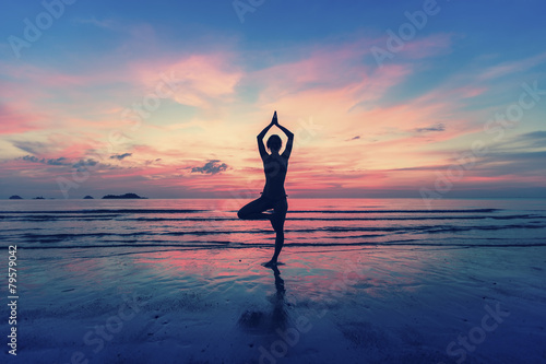 Woman standing at yoga pose on the beach during. photo