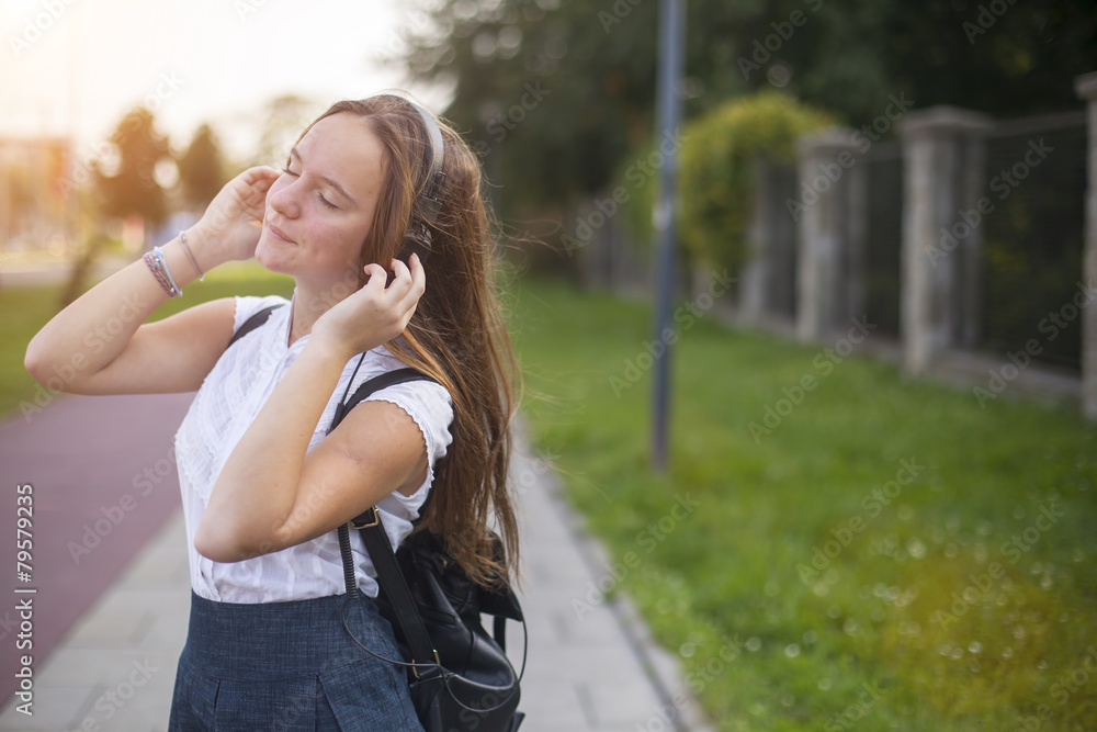 Girl enjoying music with headphones in the mild sunshine. Girl enjoying music with headphones in the mild sunshine.