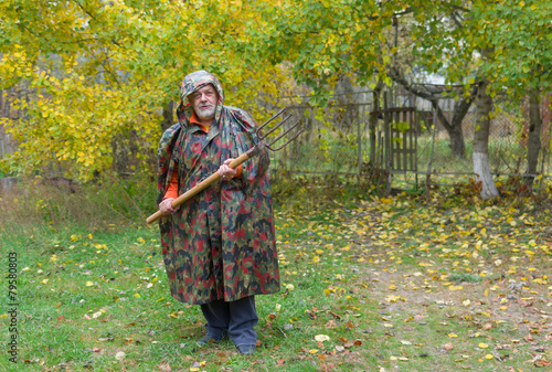 Elderly pleasant defend his farmstead entry with pitchfork © Yuri Kravchenko