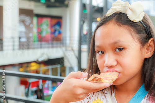 Asian girl child eat pizza in restaurant