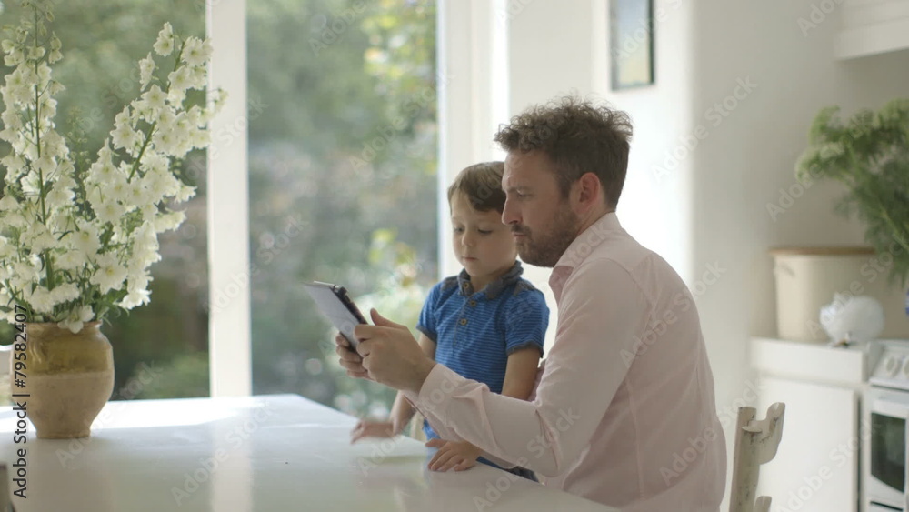 Father and son using digital tablet in domestic room Father and son using digital tablet in domestic room