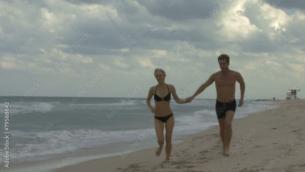 Couple holding hands walking along a beach Couple holding hands walking along a beach