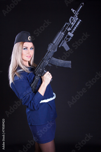 Beautiful young woman in a marine uniform with an assault rifle