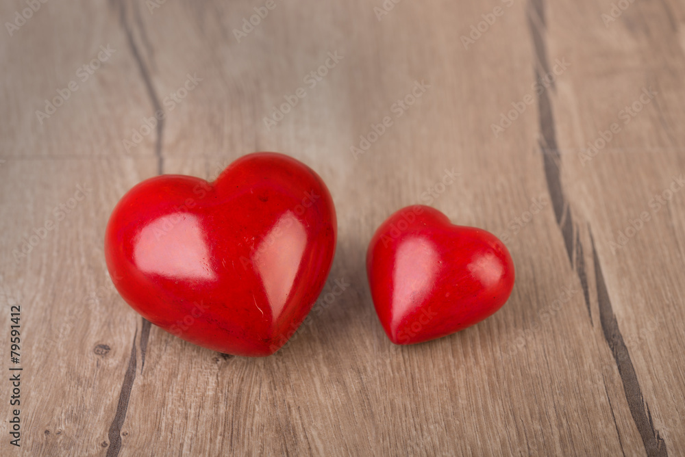 Two red stone hearts on wooden surface