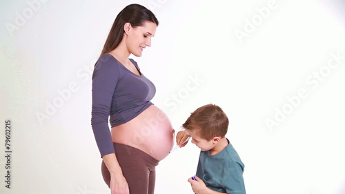 young boy draws hearts and kisses the belly of his mother