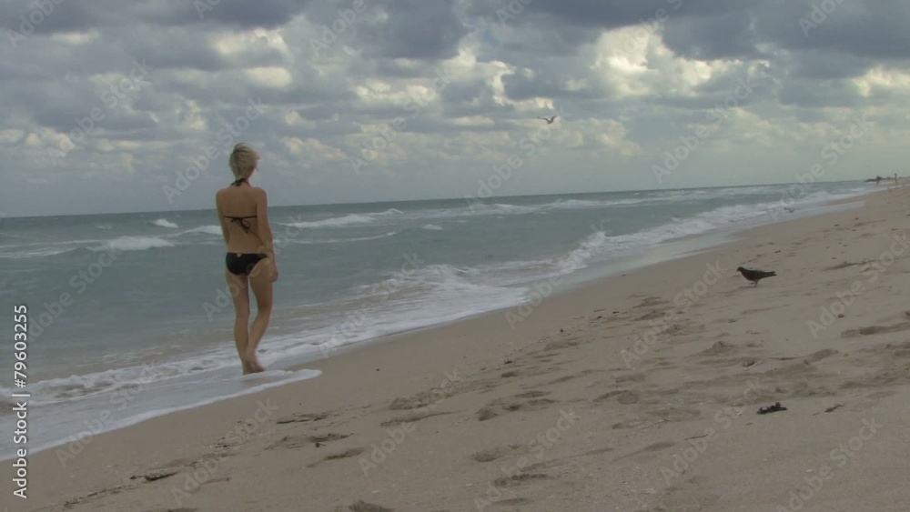 Female walking down a beach on her own Female walking down a beach on her own
