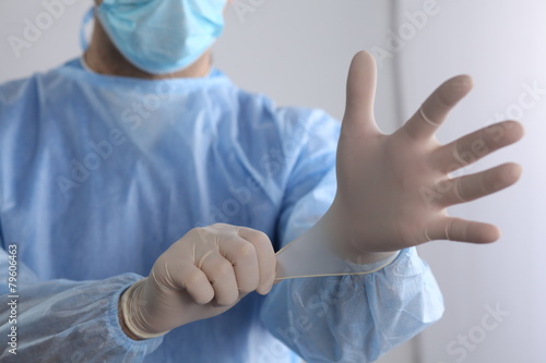 Male doctor putting on disposable gloves