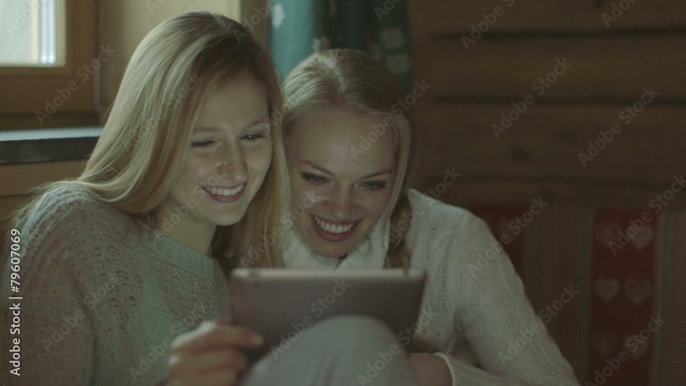 Young women using digital tablet in chalet Young women using digital tablet in chalet