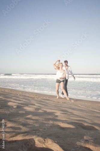 Young beautiful couple playful at the beach flirting in love