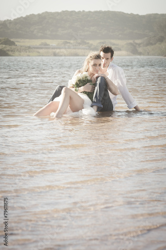 Young beautiful couple sitting in water flirting in love
