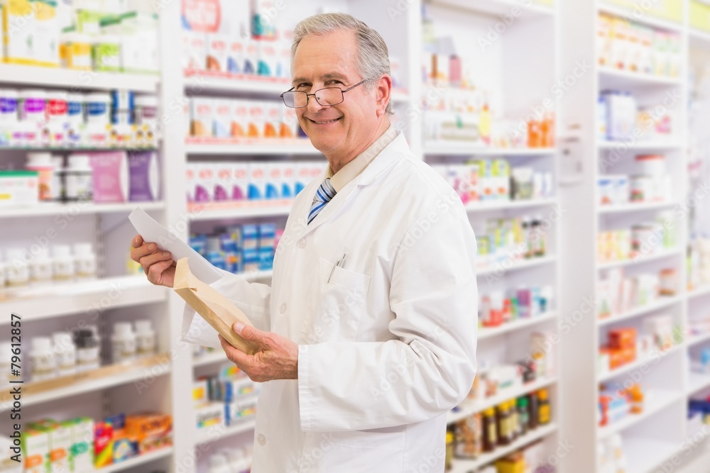 Smiling senior pharmacist holding envelope and prescription