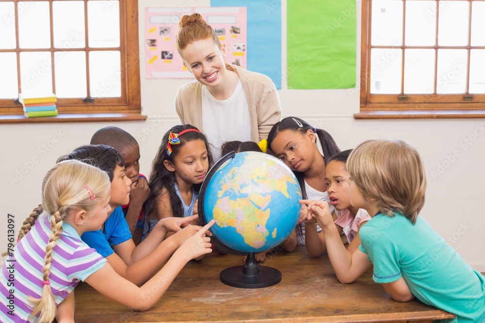 Fototapeta premium Cute pupils and teacher in classroom with globe