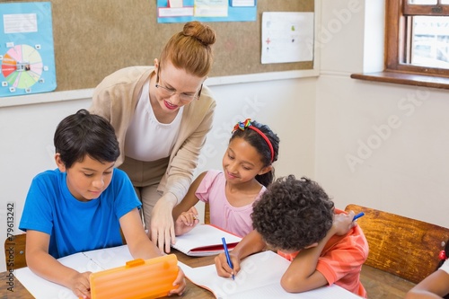 Cute pupils getting help from teacher in classroom