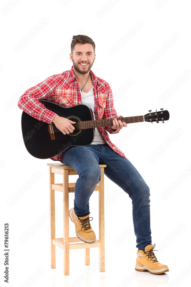 Obraz premium The guitarist posing on a chair