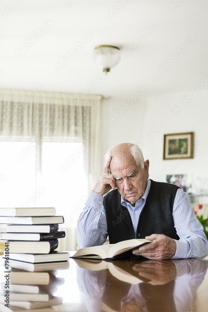 Fototapeta premium Senior man reading book relaxed at home