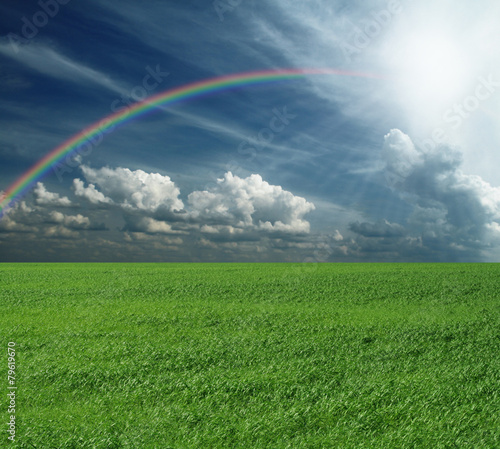 green grass and blue cloudly sky with rainbow