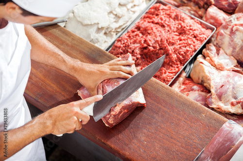 Smiling Butcher Cutting Meat At Counter photo