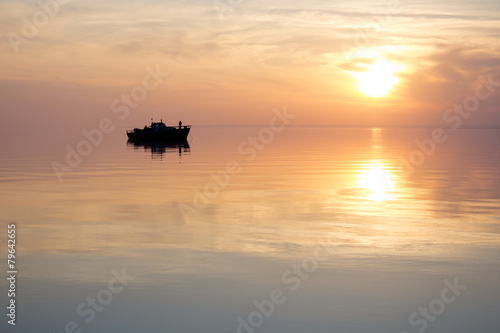 silhouette of a floating boat at sunset