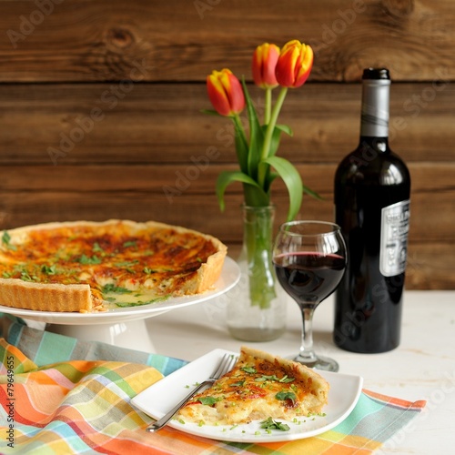 Cheese tart with red wine and red tulips on wooden background
