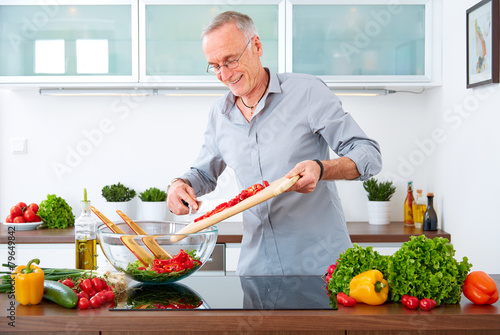 Mature man in the kitchen prepare salad IX
