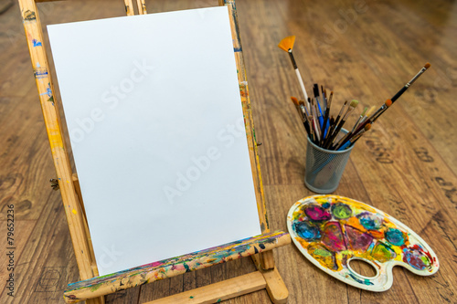 easel palette and brushes with empty white canvas