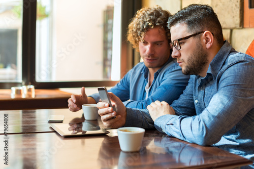 Casual guys in a Cafe looking at mobile phone