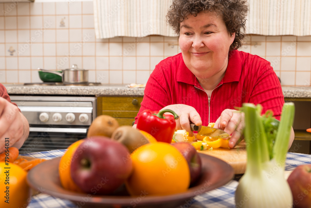 Geistig behinderte Frau schneidet Paprika am Tisch Geistig behinderte Frau schneidet Paprika am Tisch