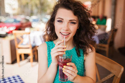 Woman in round sunglasses with cocktail at cafe terrace having f