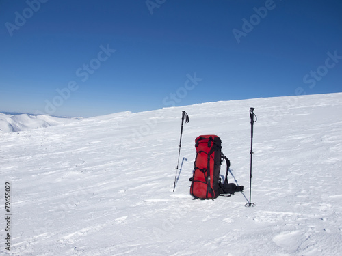 Backpack and trekking poles in the snow.