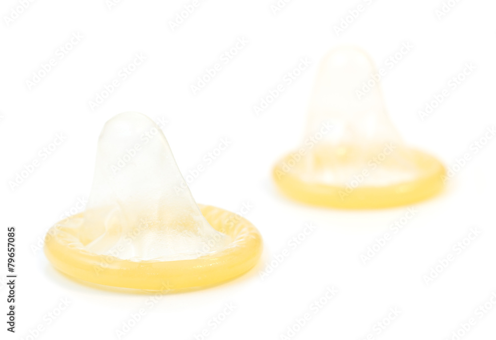 Closeup of two rolled-up condoms, isolated on white background
