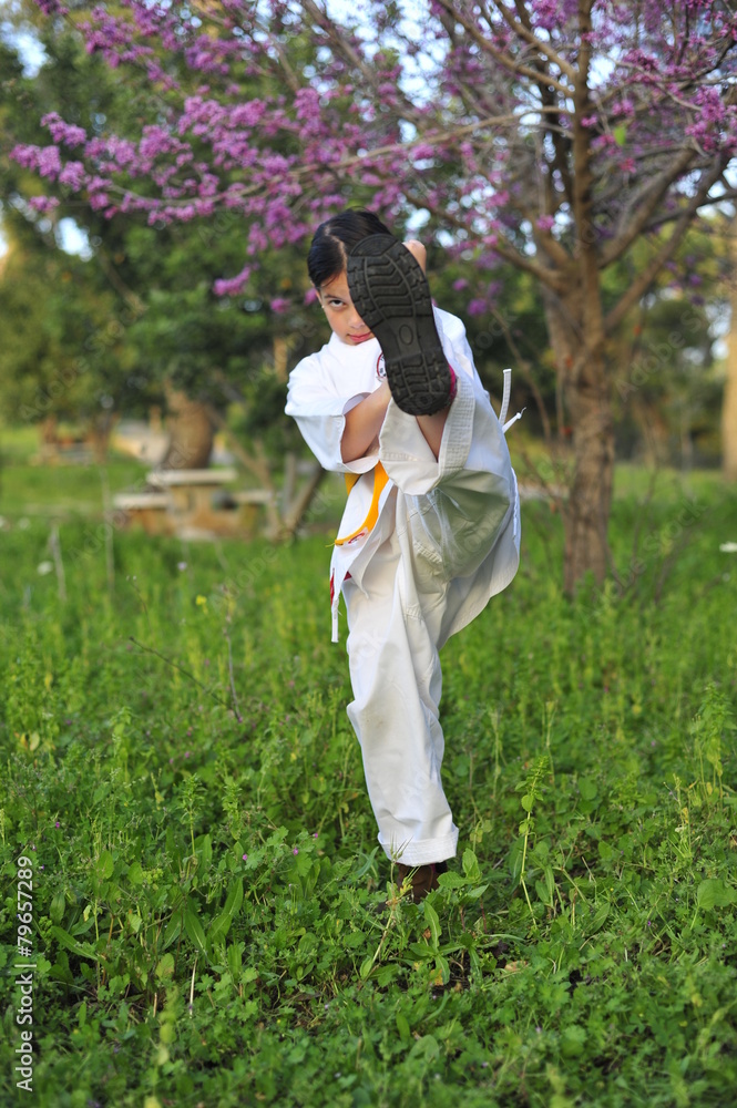 Young girl in kimono w yellow belt exercising karate.