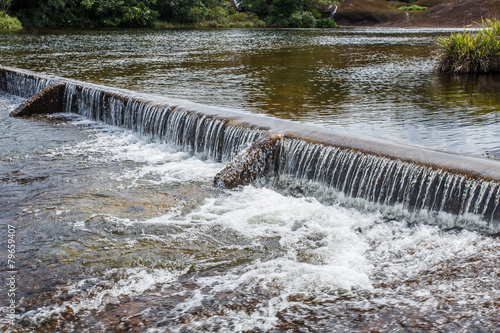 Foaming water coming over a small waterfall from a dam.