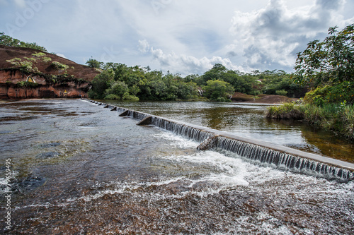 Foaming water coming over a small waterfall from a dam.