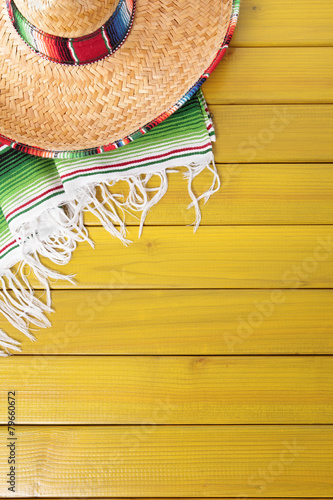 Mexican background with sombrero straw hat and traditional serape rug or blanket on old planked pine wood Mexico holiday vacation cinco de mayo photo vertical