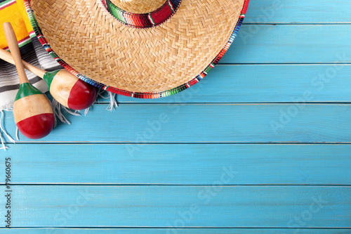 Mexican background with sombrero straw hat maracas and traditional serape rug or blanket on old planked blue wood Mexico holiday vacation cinco de mayo photo 