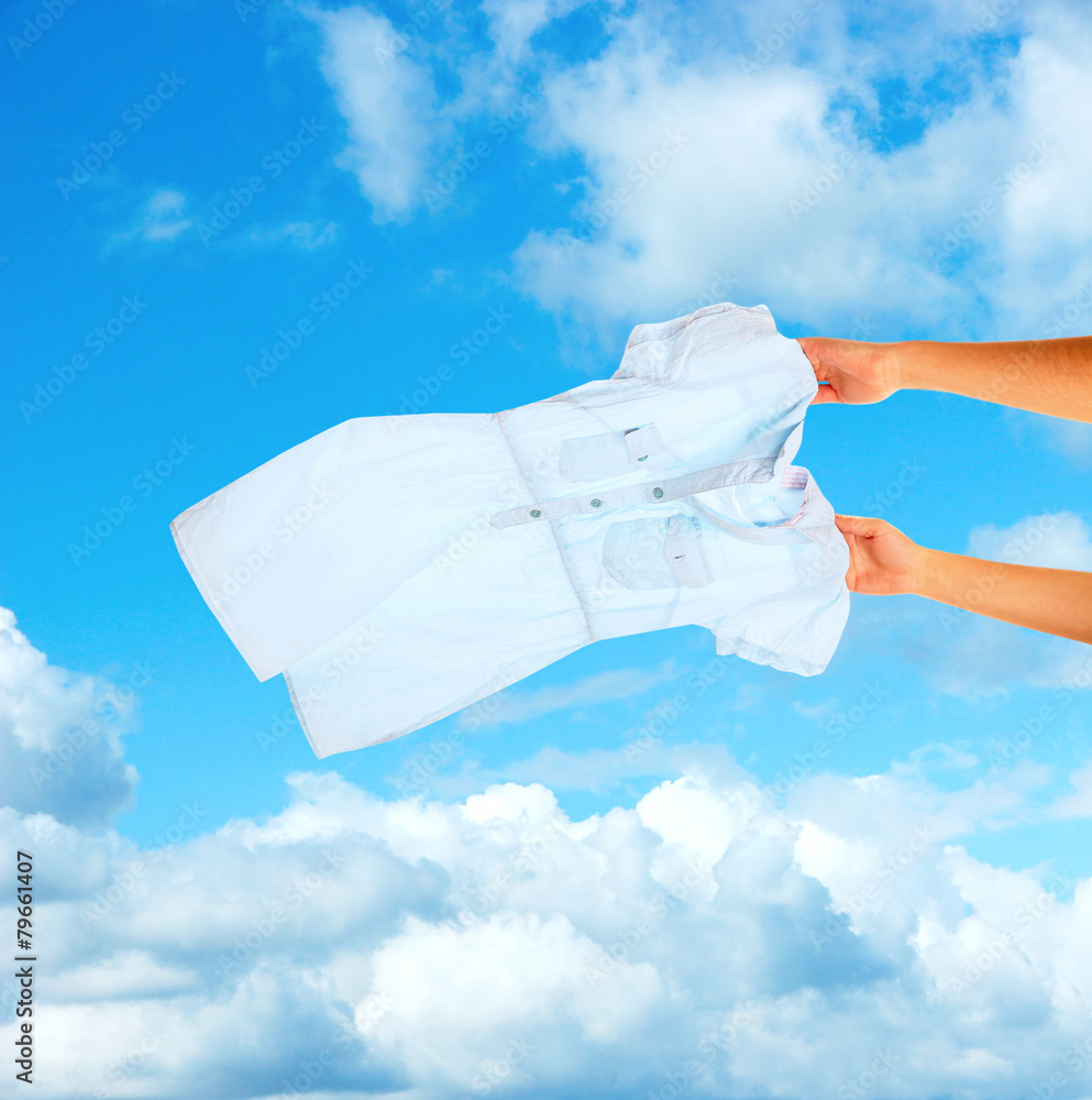 Fototapeta premium Hands holding flying shirt on sky background