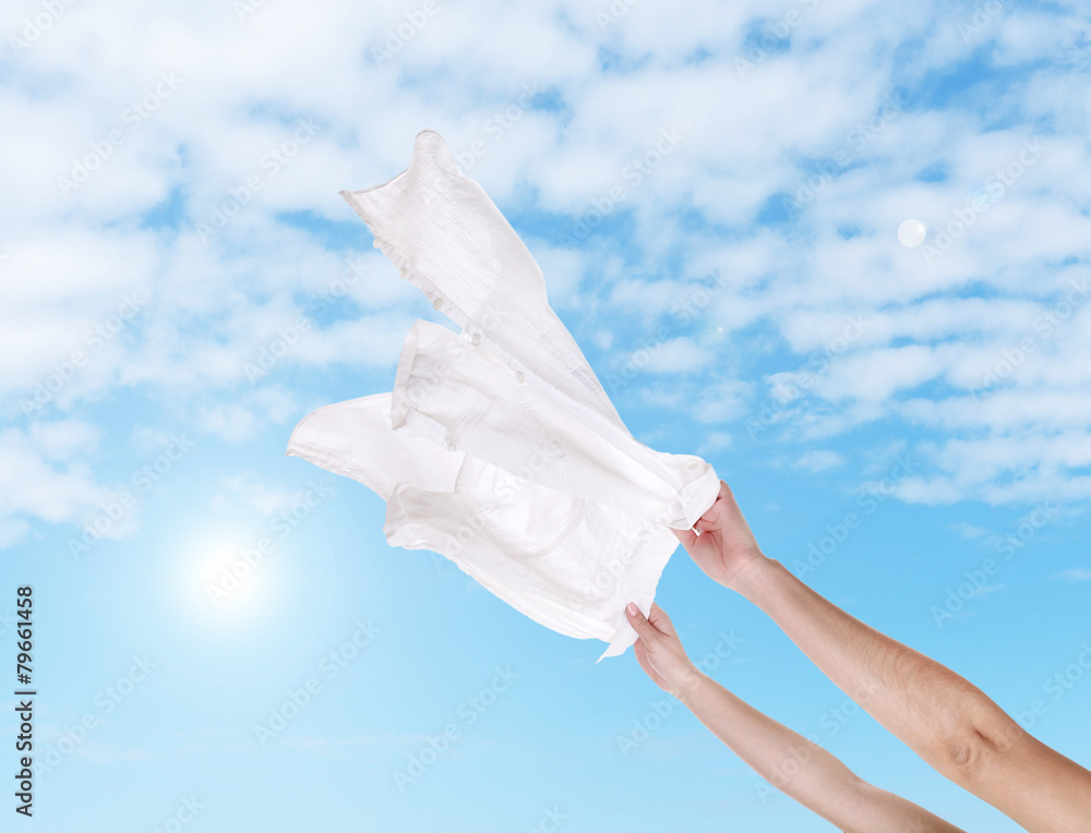 Hands holding flying shirt on sky background Hands holding flying shirt on sky background