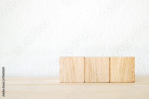 Fototapeta Naklejka Na Ścianę i Meble -  Three wooden cubes on table over white wall background